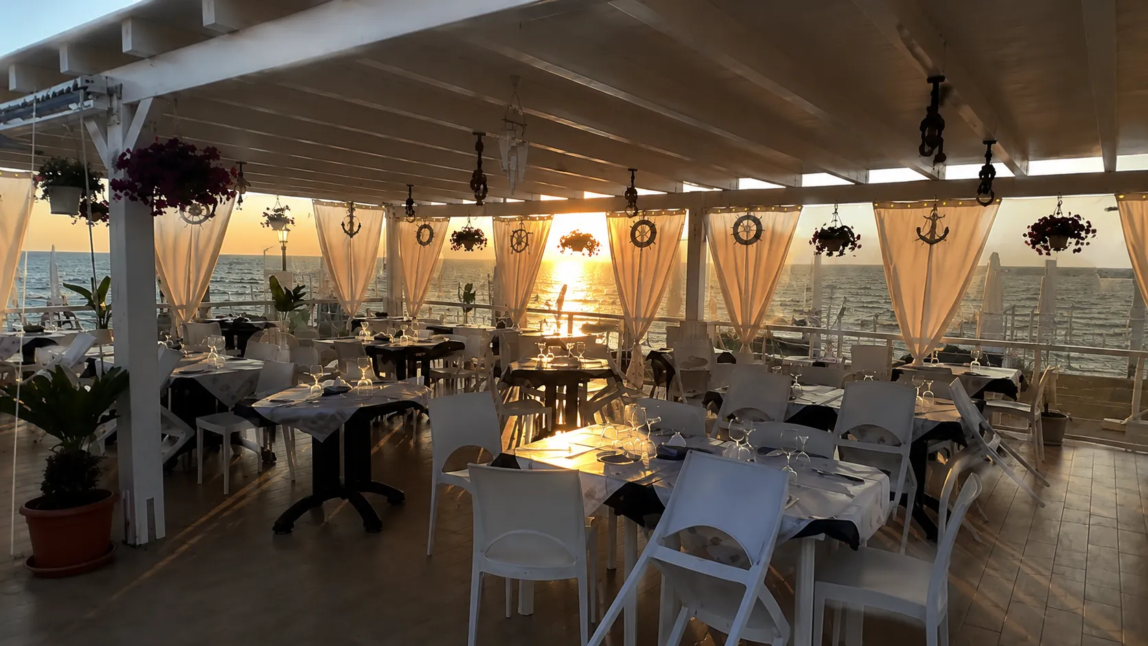 La veranda del Golden Beach al tramonto, tavoli apparecchiati vista mare
